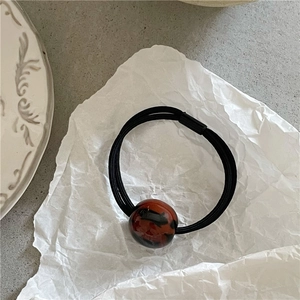Close-up of leopard pattern marble bead on black elastic hair tie with white background
