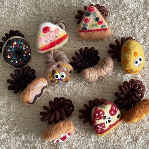 Detailed view of handmade felt food hair ties with pizza and donut shapes on textured fabric