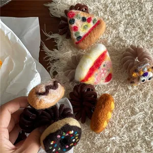 Detail of handmade felt hair ties featuring pizza, donut, and cookie food shapes