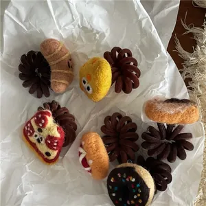 Detailed close-up of cute handmade wool felt food hair ties on white paper