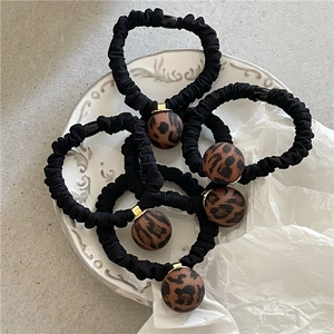 Detail view of five black elastic hair ties with leopard print beads on a ceramic plate