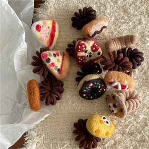 Close-up of handmade felt food hair ties with pizza and donut shapes on plush background