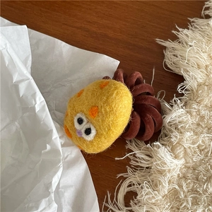 Close-up of yellow felt monster hair tie with googly eyes and brown spiral band