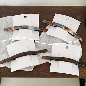 Detail of four acetate hair clips in marble and tortoiseshell patterns with metal clips