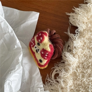 Close-up of handmade felt pizza hair tie with brown spiral cord on aesthetic background