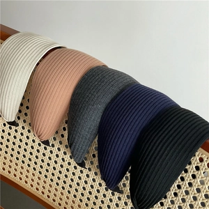 Detail view of five assorted color vertical rib knit wide headbands on a wooden chair