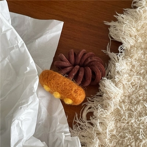 Close-up of cute wool felt pizza hair tie set on a natural wooden and fabric background