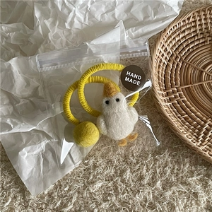 Detail eines handgemachten Enten-Haargummis aus Filz mit gelbem Gummiband verpackt