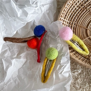 Detailed macro view of handmade wool felt ball hair clips in three vibrant color sets