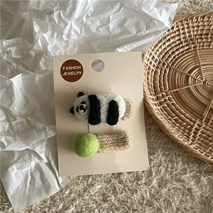Detail von Wollfilz-Panda- und grünen Garnkugel-Haarspangen auf einer Schmuckkarte