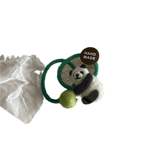 Handgefertigter Plüsch-Panda-Haargummi mit grüner Bommel auf weißem Grund
