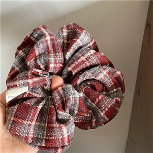 Close-up of red and grey argyle fabric scrunchie with a white handmade label