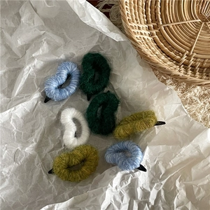 Lot de barrettes à cheveux en laine colorée sur papier blanc avec panier en osier