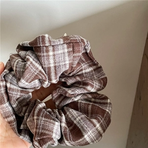 Close-up of retro plaid fabric scrunchie with brown and beige checkered patterns