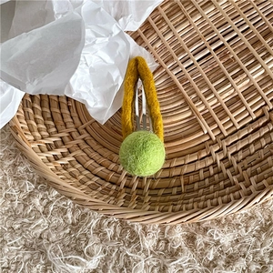 Detail of wool felt hair clip with yellow felt wrap and light green pompom on metal base