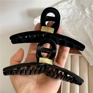 Nahaufnahme von Haarklammern aus Samt und Harz mit goldenen Metalldetails in der Hand