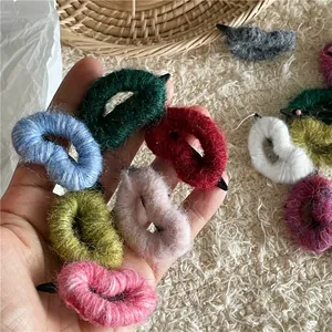 Détail de pinces à cheveux cœur en laine tricotée colorée montrant la texture douce