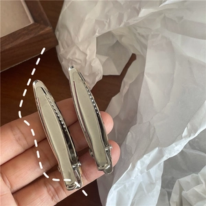 Détail de deux pinces à cheveux ovales en argent minimalistes au fini miroir poli