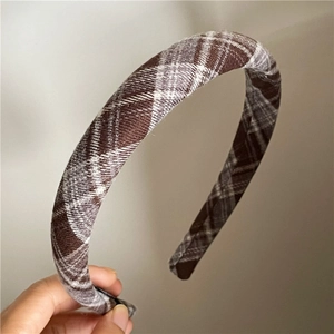 Close-up of thick plaid headband featuring a brown and grey check pattern texture
