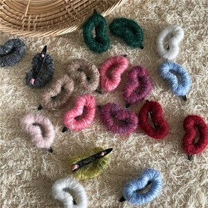 Gros plan de barrettes à cheveux en tricot colorées en forme de cœur sur peluche blanche