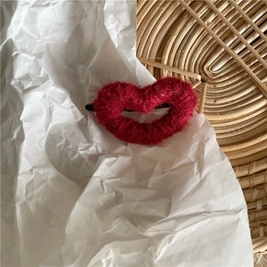Gros plan détaillé d'une pince à cheveux cœur en laine rouge sur fond d'osier vintage
