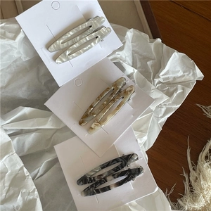 Trois paires de barrettes ovales en acétate avec texture marbrée sur papier minimaliste