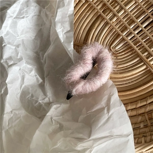 Détail d'une pince à cheveux cœur en peluche rose avec texture mohair sur tapis