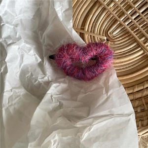 Détail d'une pince à cheveux en forme de cœur avec des fibres de laine rose et violet