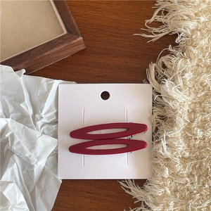 Détail de pinces à cheveux en acétate rouge ajourées sur fond de table en bois