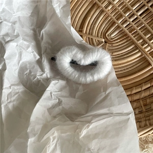 Gros plan d'une jolie pince à cheveux en forme de cœur avec une peluche blanche toute douce