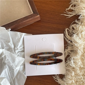 Détail de barrettes ovales évidées en acétate avec motif écaille de tortue sur carte