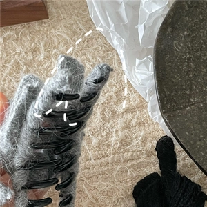 Close-up detail of grey knitted wool texture and black plastic claws of the hair clip