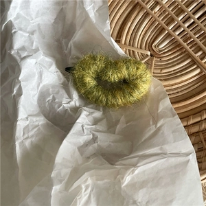 Gros plan d'une pince à cheveux en forme de cœur crocheté vert sur fond blanc