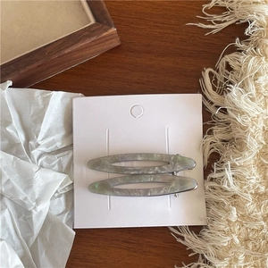Détail de barrettes ovales évidées en acétate avec texture marbre gris sur carte