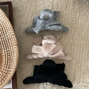 Winter plush knitted bow hair claws in grey, apricot and black colors on beige fabric