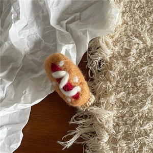 Detail einer handgemachten Hot-Dog-Haarklammer aus Filz mit roten und weißen Texturen
