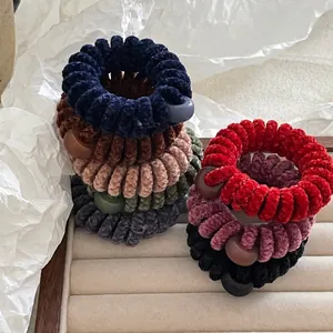 Chouchous spirales en velours colorés avec perles mates en tons d'hiver sur un plateau