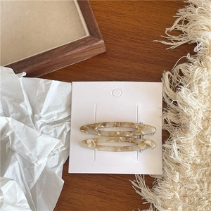 Gros plan de barrettes en acétate beige à motif marbré sur un fond en bois sombre
