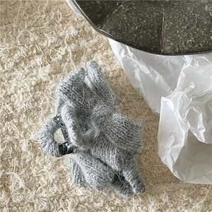 Macro detail of a grey knitted bow hair claw clip with cozy winter faux fur texture