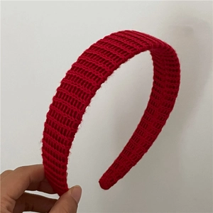 Détail d'un bandeau en tricot rouge montrant la texture épaisse et le tissage en laine
