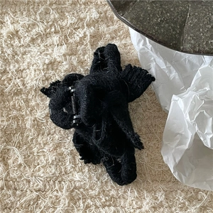 Close-up of black knitted bow hair claw clip showing soft texture and spring structure