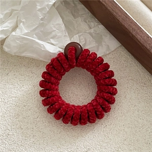Détail macro d'un chouchou spirale en velours rouge avec perle sur support