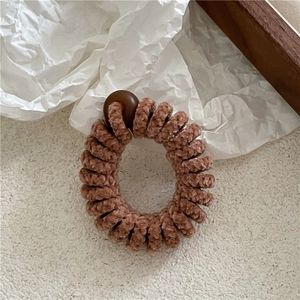 Gros plan sur l'élastique spirale marron floqué avec une perle ronde décorative