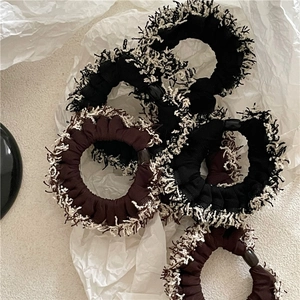 Detailed view of black and brown scrunchies with white fringe edges for winter styling