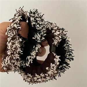 Handheld view of two-piece fringe scrunchie set in stylish brown and white textured fabric