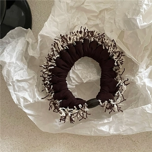 Close-up of brown tweed scrunchie with fringe edges and black oval decorative bead
