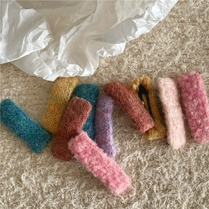 Gros plan de barrettes à cheveux tricotées colorées en laine mohair sur un fond crème doux