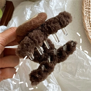 Detailed close-up of brown plush hair claw clip with sturdy transparent acrylic teeth