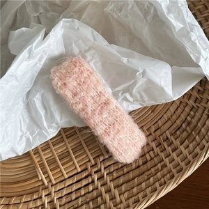 Détail d'une pince à cheveux rectangulaire rose en maille sur du papier de soie blanc