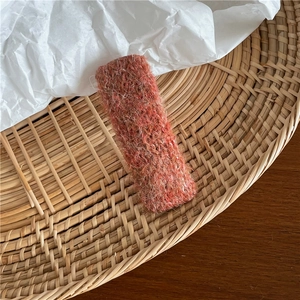 Gros plan détaillé d'une pince à cheveux rectangulaire en tricot rouge sur un plateau